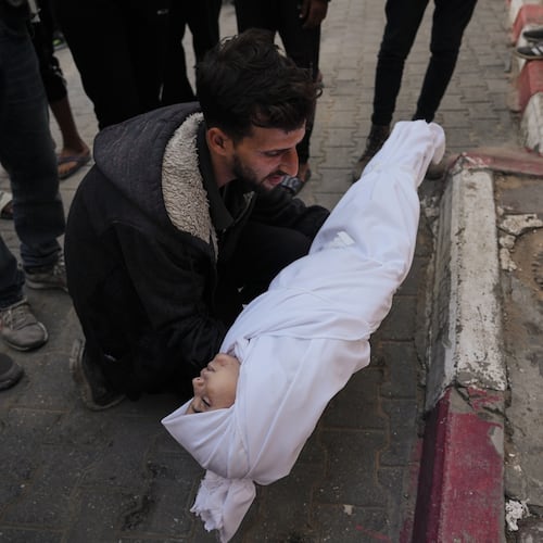 A man carries the body of a child from the Azzam family, killed in Israeli strikes, during her funeral at Shifa Hospital in Gaza City Thursday, Nov. 20, 2025. (AP Photo/Jehad Alshrafi)