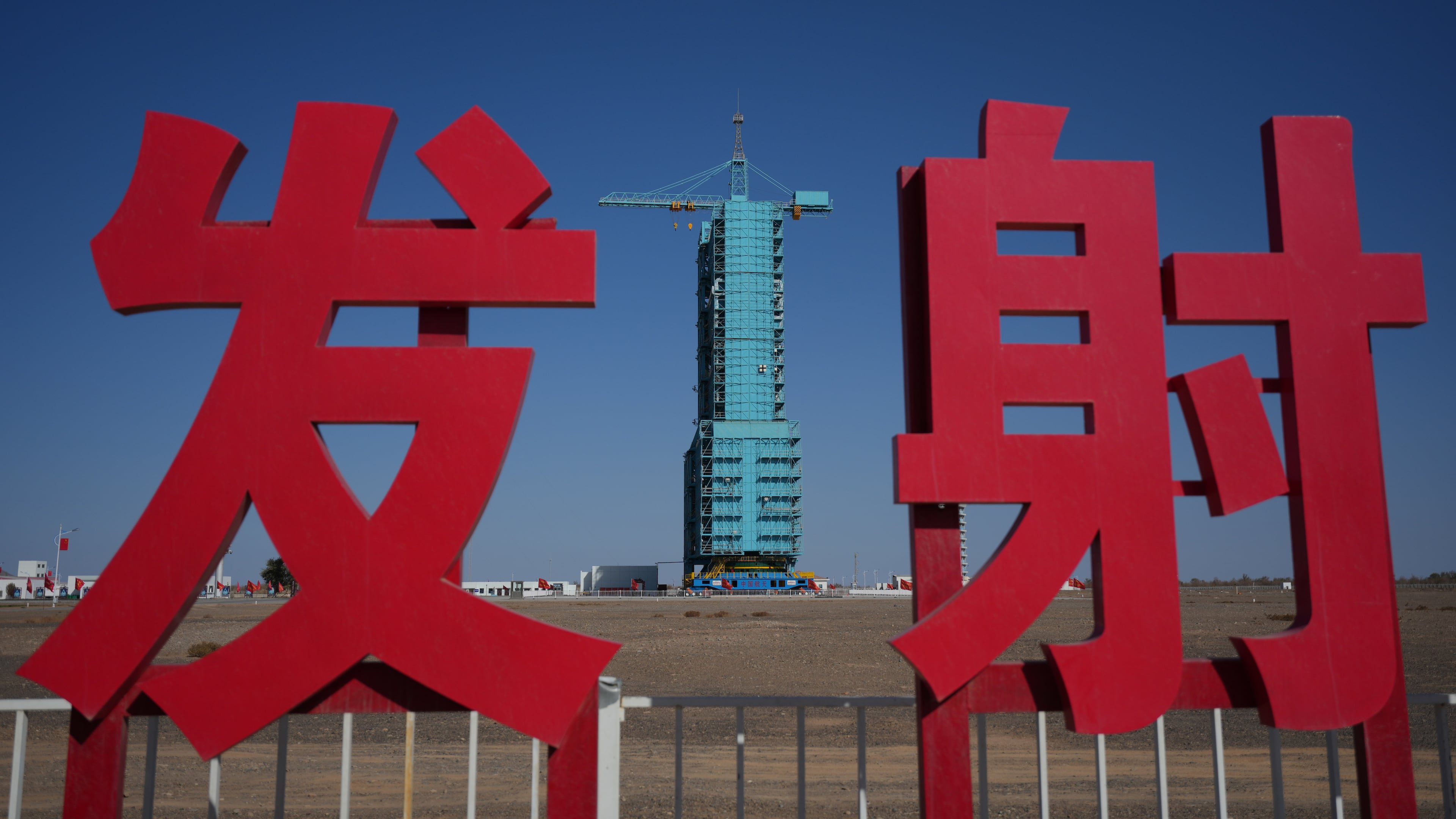 The Shenzhou-21 spacecraft sitting atop a Long March rocket covered on a launch pad is seen near the Chinese characters for launch, at the Jiuquan Satellite Launch Center in northwest China, Thursday, Oct. 30, 2025. (AP Photo/Andy Wong)