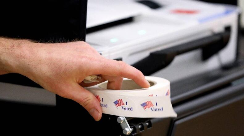 A precinct worker holds a roll of I Voted stickers next to a voting machine as voters cast their ballots at Clays Mill Elementary School on May 16, 2023, as Kentucky went the polls on primary election day. Workers at this precinct said they had 40 people vote in the first two hours the polls were open.