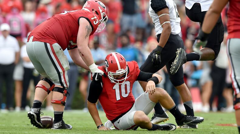 Georgia quarterback Jacob Eason is helped up by teammate Greg Pyke after he was sacked to bring up 4th and 15 in the 3rd quarter Saturday. The Bulldogs lost to Vanderbilt 17-16 on at Sanford Stadium. (Brant Sanderlin bsanderlin@ajc.com)