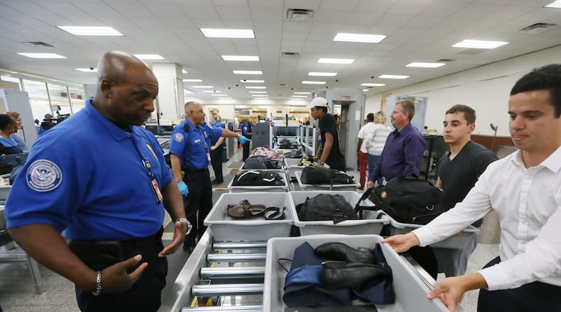 May 25, 2016 - Atlanta - TSA agent Darren Walker (left) helps passengers using the new system, where they slide their baggage onto the automated rollers. TSA unveiled new security "smart lanes" that have been installed in the South Security Checkpoint, which feature automated equipment that handles baggage. BOB ANDRES / BANDRES@AJC.COM