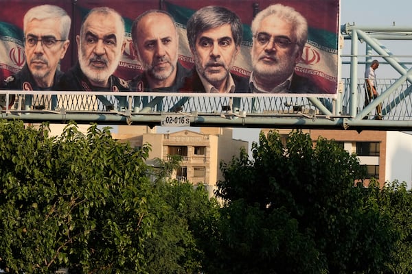 A man walks past a billboard displaying images of top Iranian commanders and scientists killed in Israeli strikes early Friday, in Tehran, Iran, Friday, June 13, 2025. (AP Photo/Vahid Salemi)