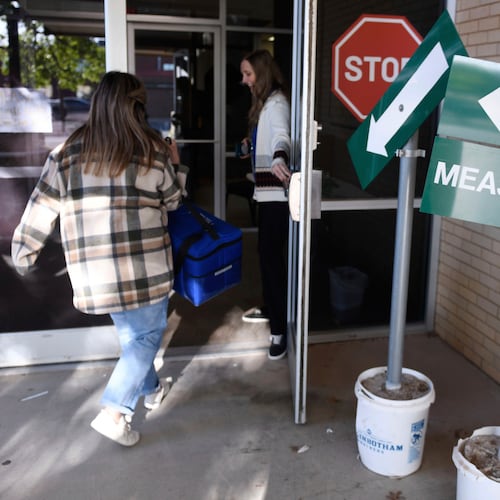 FILE - Health department staff members enter the Andrews County Health Department measles clinic carrying doses of the measles, mumps and rubella vaccine, Tuesday, April 8, 2025, in Andrews, Texas. (AP Photo/Annie Rice, File)