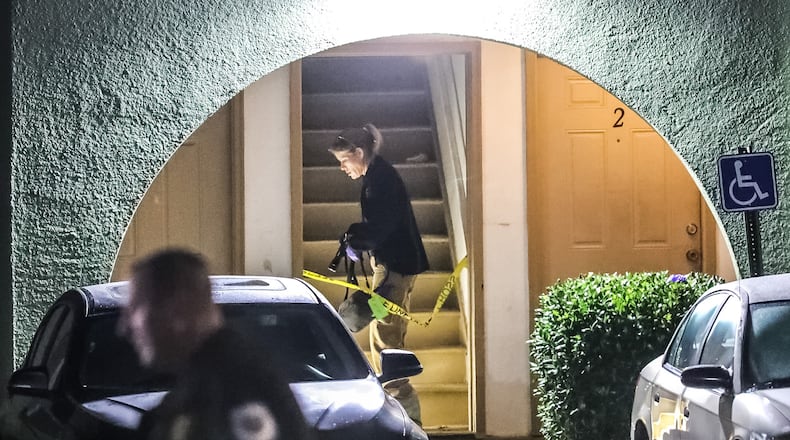 A Cobb County police officer strings crime scene tape across a breezeway at the scene of a shooting at the Mableton Ridge apartments on Mableton Parkway.