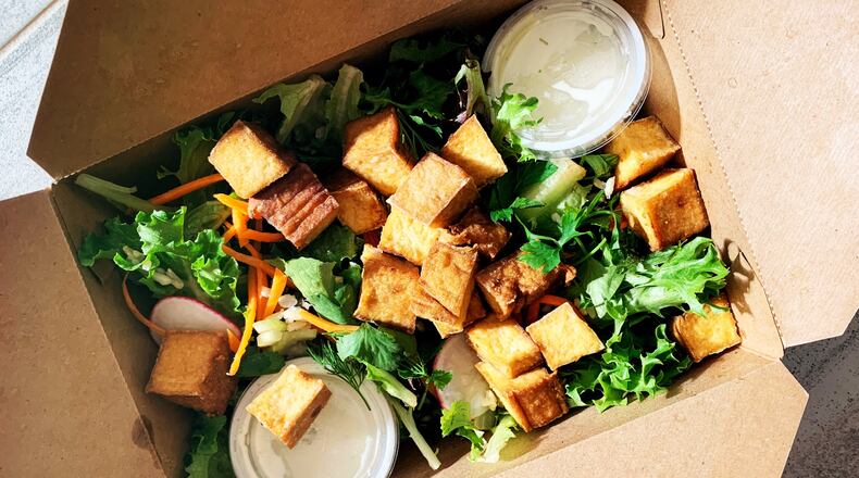 The tropical salad with smoked tofu from El Super Pan is made with local greens and topped with avocado, cherry tomatoes, palm hearts, green olives and pepitas. Henri Hollis for The Atlanta Journal-Constitution
