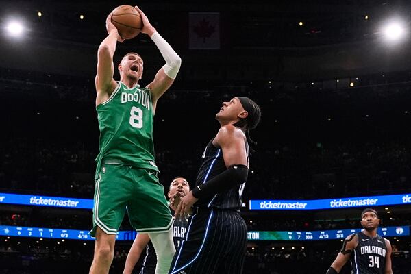 Boston Celtics center Kristaps Porzingis (8) grabs a rebound against Orlando Magic forward Paolo Banchero, right, during the first half in game 2 of a first-round NBA playoff basketball series, Wednesday, April 23, 2025, in Boston. (AP Photo/Charles Krupa)