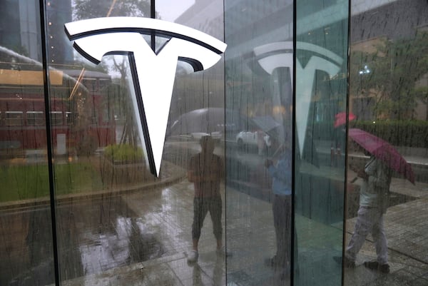 Private security guards stand amidst rain outside India's first TESLA showroom in Mumbai, India, Tuesday, July 15, 2025. (AP Photo/Rafiq Maqbool)