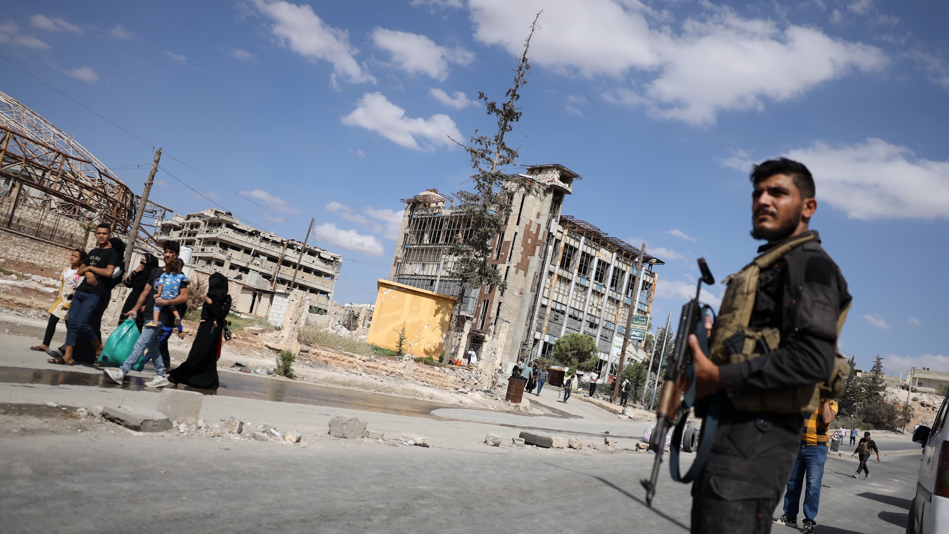 Syrian security forces stand guard as residents leave the Sheikh Maqsoud and Achrafieh neighborhoods of Aleppo, Syria, Tuesday, Oct. 7, 2025, following overnight clashes between Syrian government troops and the Kurdish-led Syrian Democratic Forces. (AP Photo/Omar Albam)