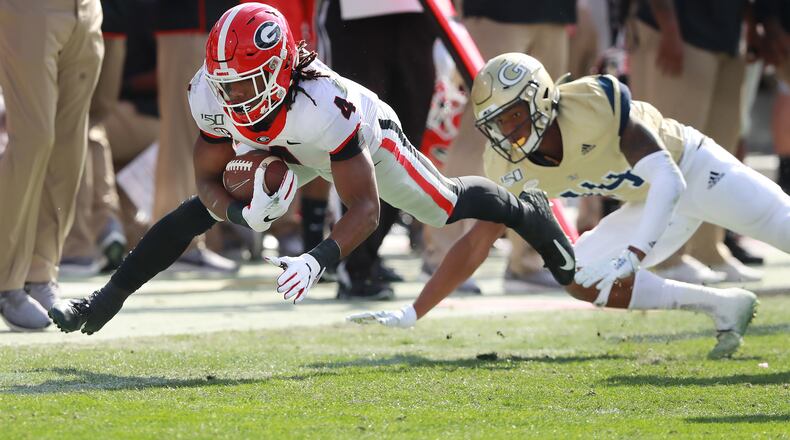 November 30, 2019 Atlanta: Georgia tailback James Cook stretches for extra yardage past Georgia Tech defender Jaylon King during the first half in a NCAA college football game on Saturday, November 30, 2019, in Atlanta.  Curtis Compton/ccompton@ajc.com