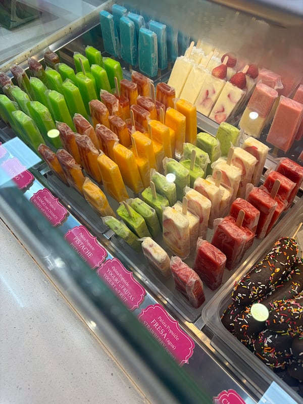 A look from above at an open freezer container in a convenience store, filled with colorful rows of popsicles called paletas.