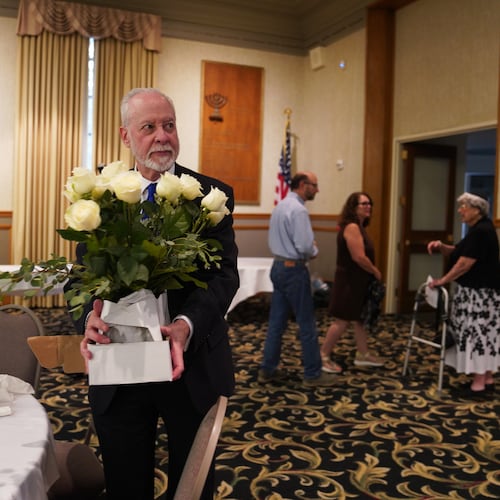 Rabbi Jeffrey Myers of the Tree of Life Congregation holds a bouquet of flowers while at his retirement dinner celebration on Friday, July 17, 2026, at Rodef Shalom Congregation in Pittsburgh. (AP Photo/Jessie Wardarski)