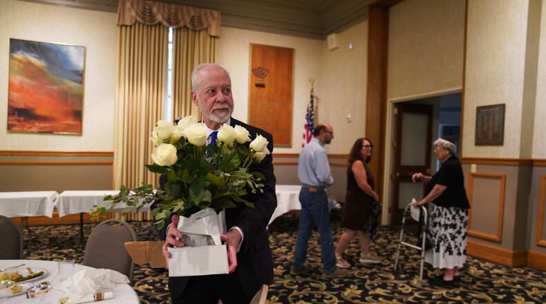 Rabbi Jeffrey Myers of the Tree of Life Congregation holds a bouquet of flowers while at his retirement dinner celebration on Friday, July 17, 2026, at Rodef Shalom Congregation in Pittsburgh. (AP Photo/Jessie Wardarski)
