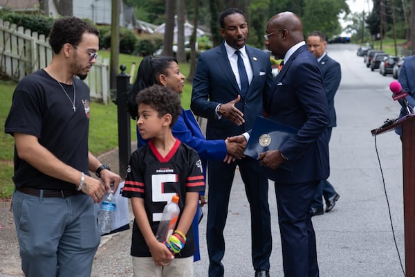“I spend my days talking to people of all walks of life, and the conversation that comes up the most is how hard it’s become to afford a place to live or to buy a home,” said Jacob Parcel (left), who brought his son Dominic, 9, to the news conference. (Ben Gray for the AJC)