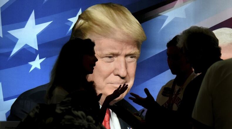 Republicans stop to talk in front of a backlit image of President Trump during the opening day of the Georgia State GOP convention Friday, June 2, 2017 in Augusta, Ga. (Michael Holahan/The Augusta Chronicle via AP)