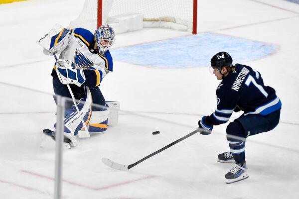 St. Louis Blues goaltender Jordan Binnington, left, clears the puck away from Winnipeg Jets' Vladislav Namestnikov (7) during the third period of Game 2 of a first-round NHL hockey playoff series in Winnipeg, Manitoba, Monday April 21, 2025. (Fred Greenslade/The Canadian Press via AP)