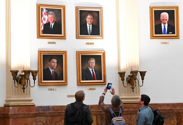 Christopher Nicklin, center, with friends Brandon Kramer, left, and Clint Denison, right, take a photo of the portrait of President Donald Trump hanging in the rotunda on the third floor of the Colorado State Capitol, Monday, March 24, 2025, in Denver. (Helen H. Richardson/The Denver Post via AP)