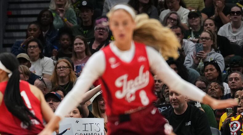 Indiana Fever guard Sophie Cunningham, front, runs by a fan holding a sign referencing her comments on transgender athletes and women's sports during the first half of a WNBA basketball game against the Seattle Storm, Tuesday, July 28, 2026, in Seattle. (AP Photo/Lindsey Wasson)