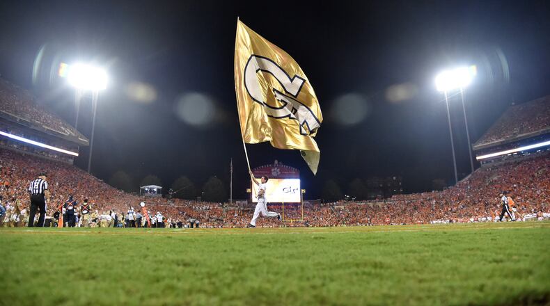 A Georgia Tech cheerleading team member runs with Tech flag across Memorial Stadium during the season opener Thursday, Aug. 29, 2019, in Clemson, S.C.