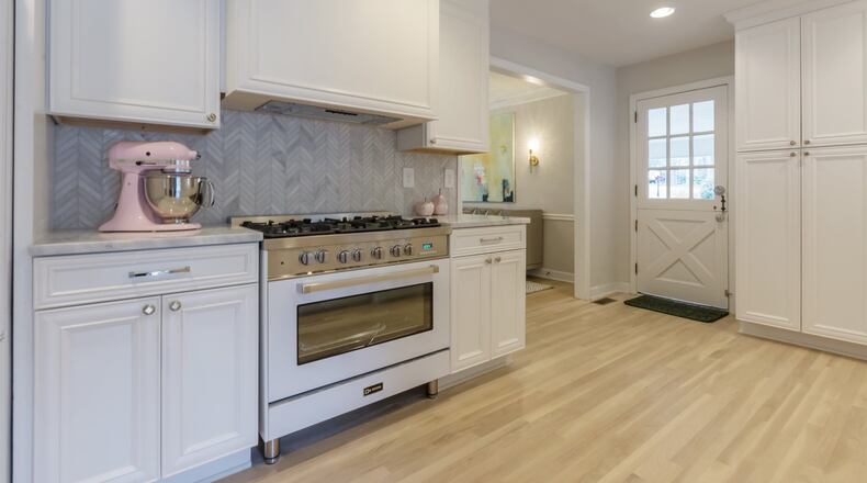 An Atlanta kitchen features white appliances and cabinetry with gray tile backsplash in a herringbone pattern. CONTRIBUTED BY Egypt Sherrod