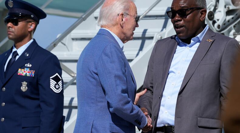 FILE - President Joe Biden, center, greets Virgin Islands Gov. Albert Bryan, Jr., right, before boarding Air Force One at Henry E. Rohlsen Airport in Christiansted, St. Croix, U.S. Virgin Islands, Dec. 31, 2024. (AP Photo/Susan Walsh, File)