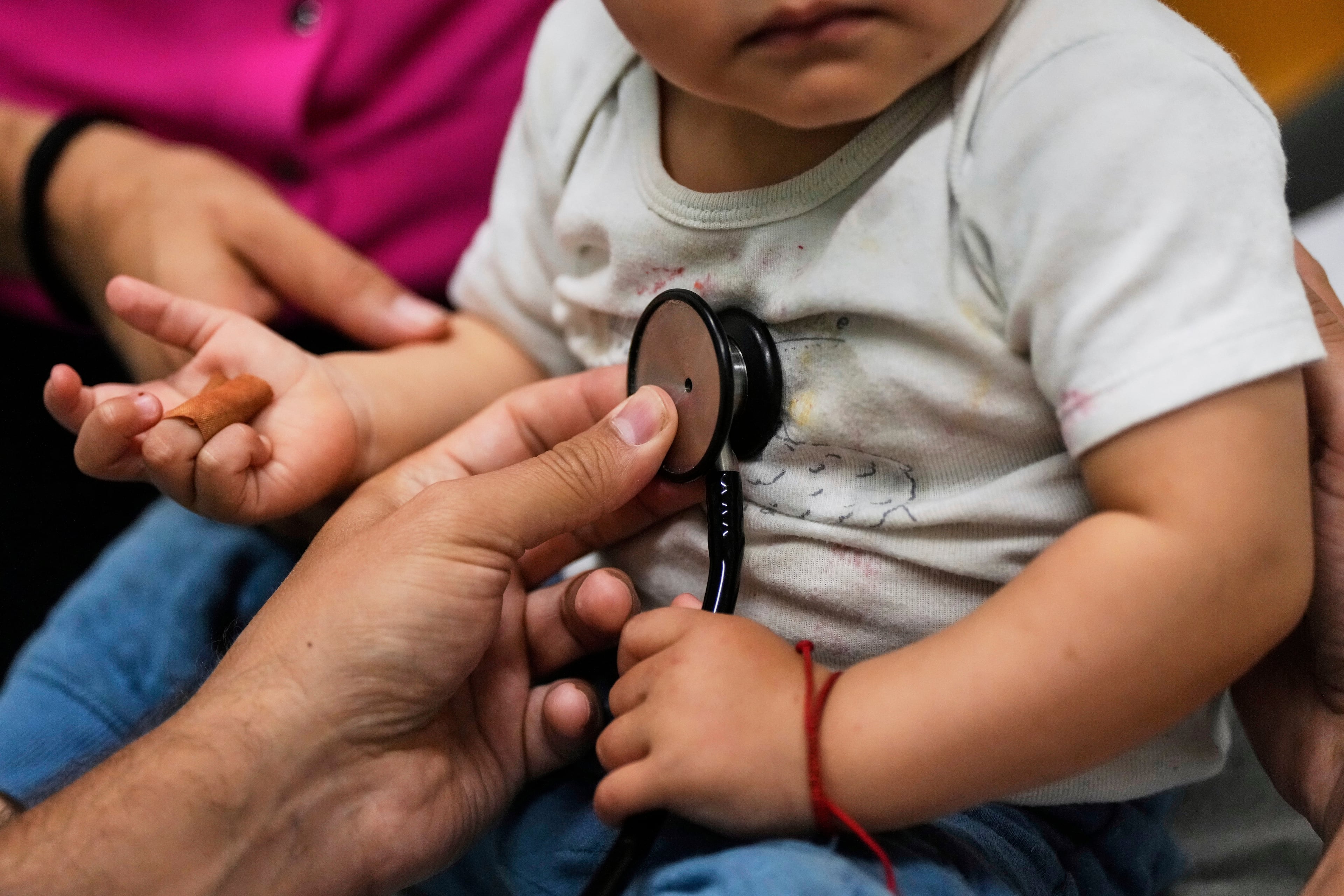 Pediatrician Irving Phillips, left, examines a 16-month-old boy at a clinic in Davis, California. Approximately 85% of uninsured Georgians live in working households but remain uninsured due to issues with affordability or eligibility. And Medicaid funding is now in shambles because of the not so “big beautiful bill." (Godofredo A. Vásquez/AP)