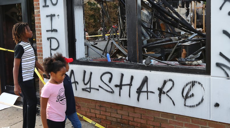 Children take in the burned out Atlanta Wendy’s where Rayshard Brooks, a 27-year-old black man, was shot and killed by Atlanta police Friday evening during a struggle in the drive-thru line on Monday, June 15, 2020, in Atlanta. Curtis Compton ccompton@ajc.com