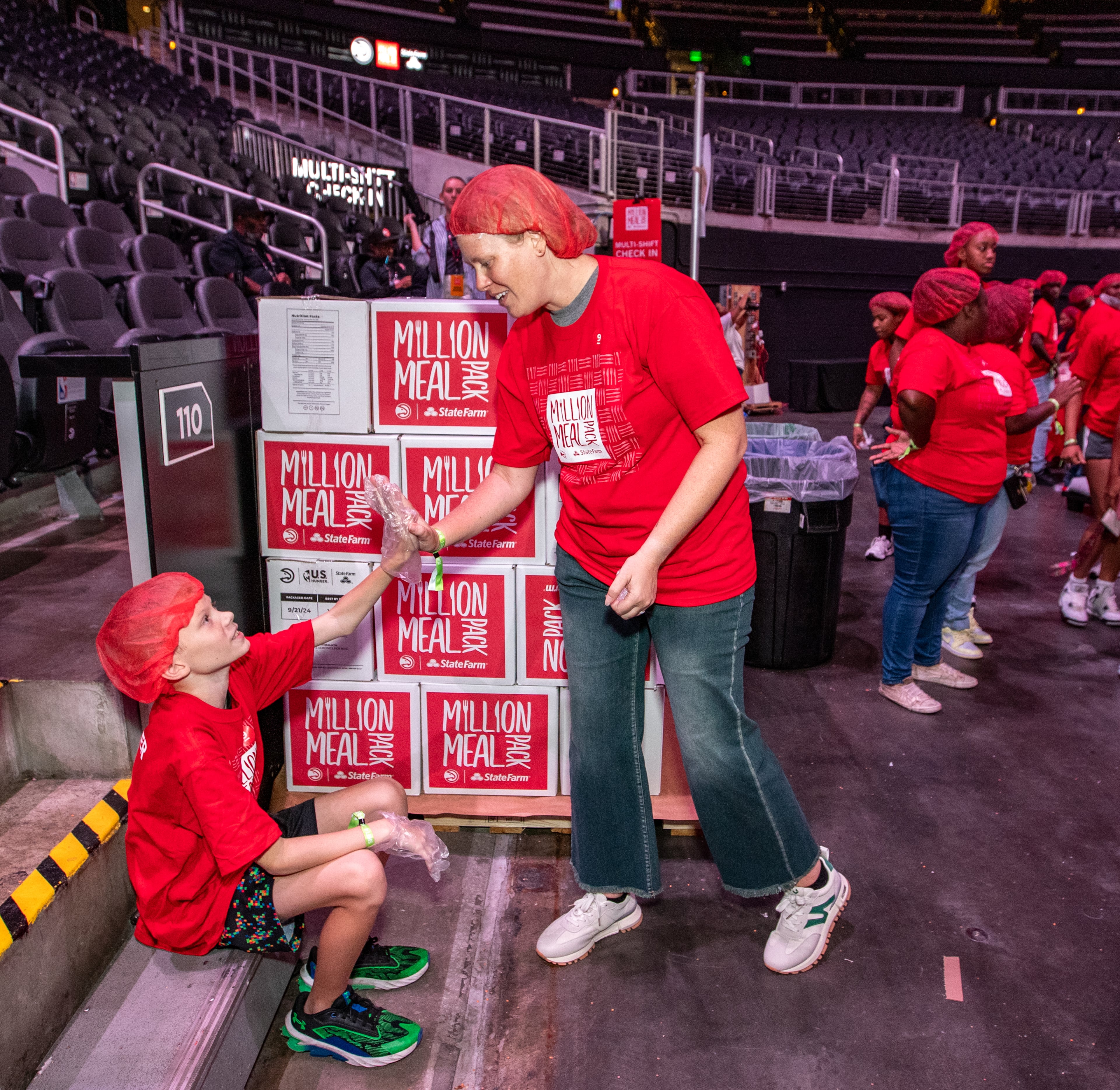 Russell Savage gets props from his mom, Lacy, after packing red lentil jambalaya kits during the Million Meal Pack at State Farm Arena on Saturday, Sept. 21, 2024, in Atlanta. (Jenni Girtman for the AJC)
