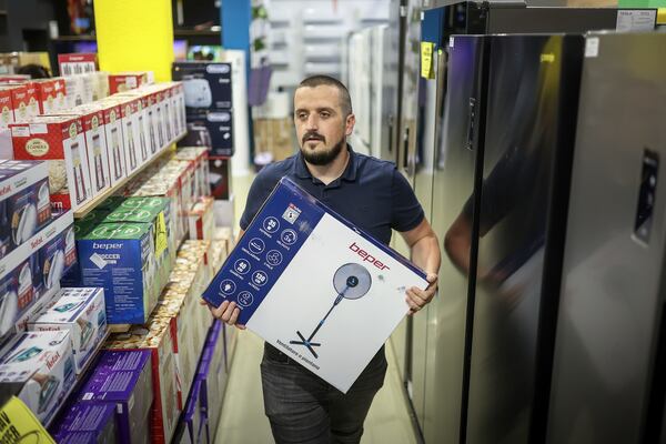 Tarik Fatic, one of the owners of "Only fools and horses ltd." home appliance store, brings a fan to a customer in Hadzici, suburb of Sarajevo, Bosnia, Wednesday, June 4, 2025. (AP Photo/Armin Durgut)