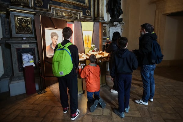 Young boys pray in front of the heart relic of Carlo Acutis, the 15-year-old Italian boy who died in 2006 of leukemia and beatified in 2020, in the San Rufino Cathedral in Assisi, Italy, Wednesday, April 2, 2025. (AP Photo/Alessandra Tarantino)