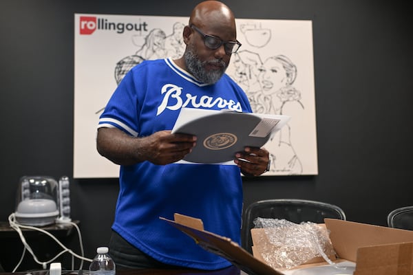 Richard Dunn, co-founder of Rolling Out Magazine and Rolling Out Music Co., looks over a new vinyl record for one of the label’s artists on Tuesday, June 30, 2026. Rolling Out Music Co. is a new label formed by the media company that focuses on independent artists. (Natrice Miller for the AJC)