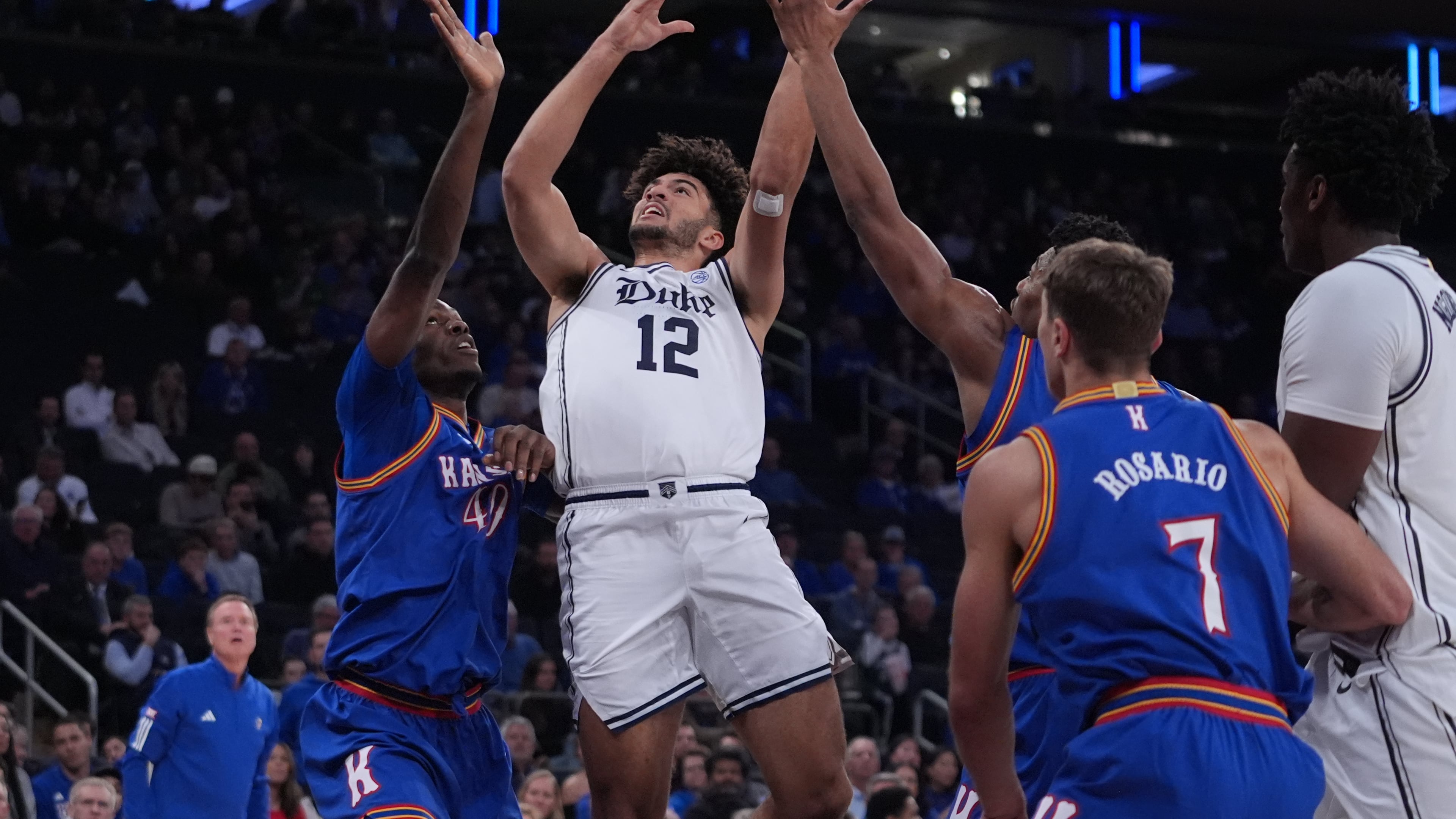 Duke's Cameron Boozer (12) drives past Kansas' Flory Bidunga (40) and Kohl Rosario (7) during the first half of an NCAA college basketball game Tuesday, Nov. 18, 2025, in New York. (AP Photo/Frank Franklin II)