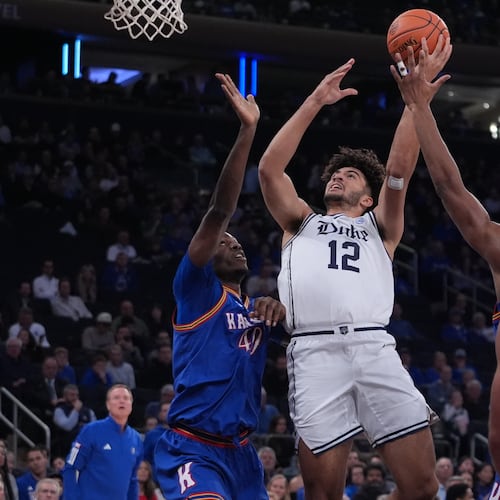 Duke's Cameron Boozer (12) drives past Kansas' Flory Bidunga (40) and Kohl Rosario (7) during the first half of an NCAA college basketball game Tuesday, Nov. 18, 2025, in New York. (AP Photo/Frank Franklin II)