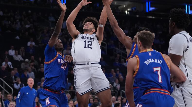 Duke's Cameron Boozer (12) drives past Kansas' Flory Bidunga (40) and Kohl Rosario (7) during the first half of an NCAA college basketball game Tuesday, Nov. 18, 2025, in New York. (AP Photo/Frank Franklin II)