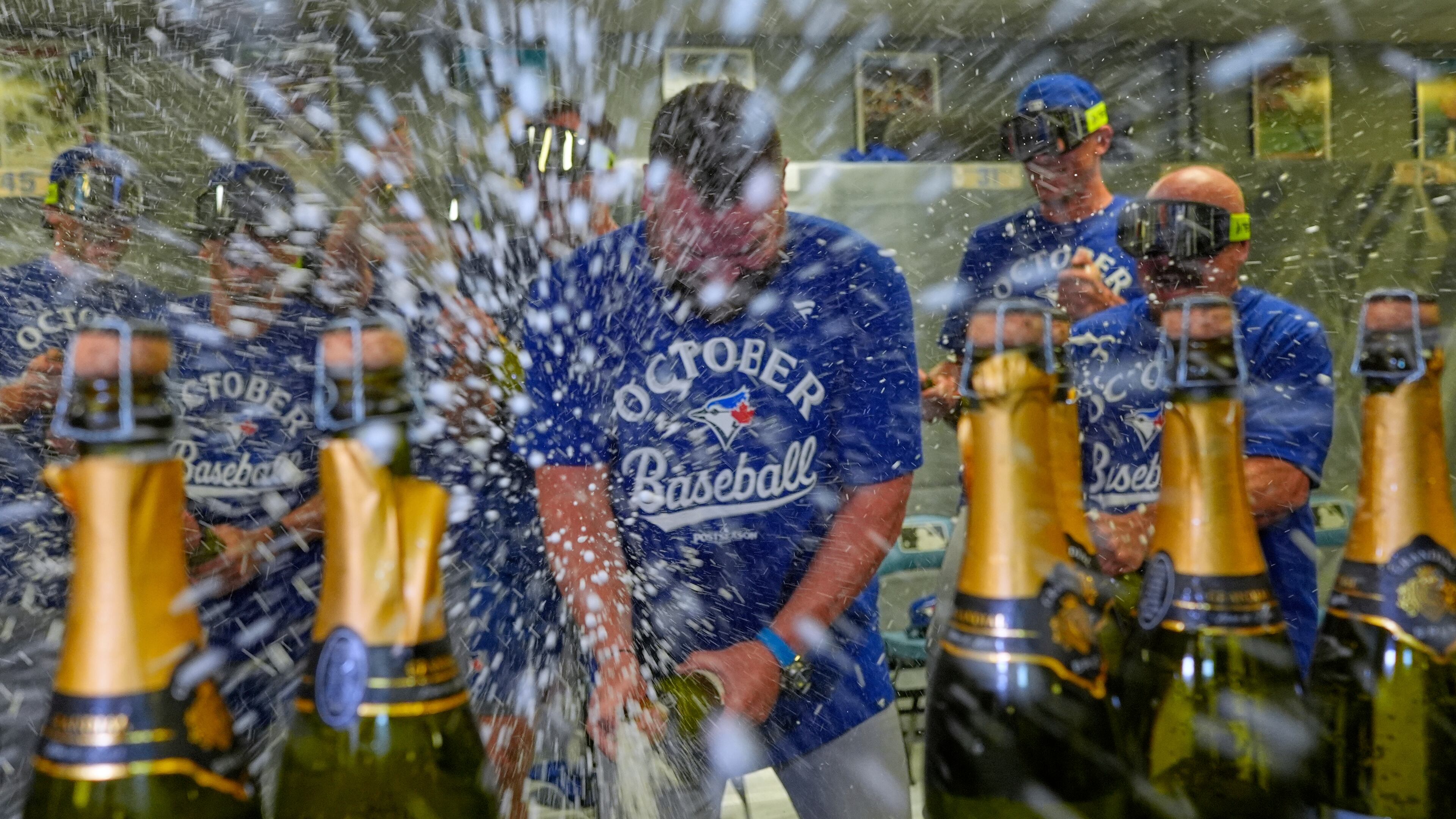 Toronto Blue Jays manager John Schneider, center, celebrates with players in the clubhouse after their a baseball game against the Kansas City Royals, Sunday, Sept. 21, 2025, in Kansas City, Mo. (AP Photo/Charlie Riedel)