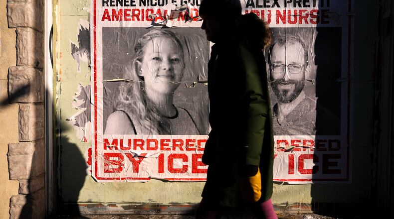 FILE - A woman walks by posters of Renee Good and Alex Pretti during a solidarity bike ride for Pretti, Jan. 31, 2026, in Minneapolis. (AP Photo/Julia Demaree Nikhinson, File)