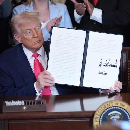 President Donald Trump displays an signed executive order as first lady Melania Trump watches during an event on foster care in the East Room of the at the White House, Thursday, Nov. 13, 2025, in Washington. (AP Photo/Evan Vucci)