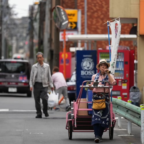 Akiko Sugaya blows an old-style horn while she peddles tofu, prepared food and beverages in a cart in Tokyo, Saturday, July 4, 2026. (AP Photo/Hiro Komae)