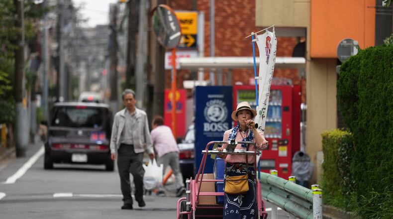 Akiko Sugaya blows an old-style horn while she peddles tofu, prepared food and beverages in a cart in Tokyo, Saturday, July 4, 2026. (AP Photo/Hiro Komae)