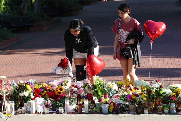 Students place flowers on a stretch of sidewalk near the center of the Florida State campus in sight of the Student Union building, Tallahassee, Fla., Friday, April 18, 2025. (AP Photo/Gary McCullough)