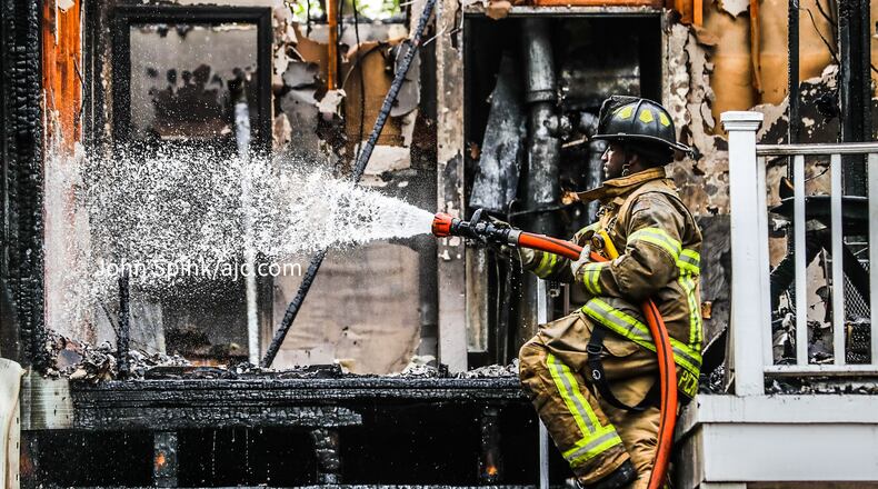 DeKalb County firefighter D’Ante Pickett sprays the upper floors of a building that caught on fire at the Northlake Manor Condominiums in Tucker on Friday morning.