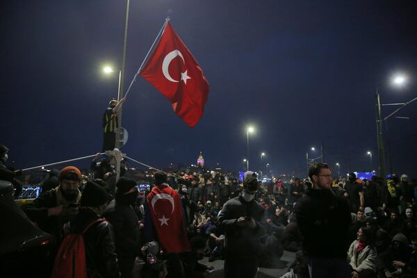 University students sit at Galata bridge during a protest after Istanbul's Mayor Ekrem Imamoglu was arrested and sent to prison, in Istanbul, Turkey, Monday, March 24, 2025. (AP Photo/Huseyin Aldemir)