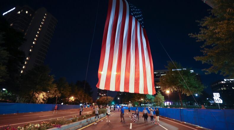 7/3/21 - Atlanta, GA - Volunteers raise the flag at the start as the AJC Peachtree Road Race returned in-person Saturday for the holiday tradition.  (Jason Getz for the Atlanta Journal-Constitution)