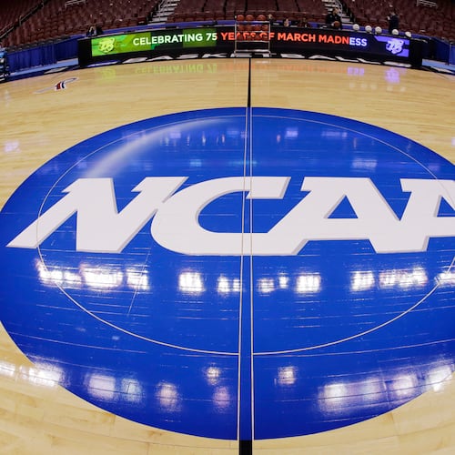 FILE - This photo taken with a fisheye lens shows the NCAA logo displayed at mid-court in Philadelphia, March 21, 2013. (AP Photo/Matt Slocum, File)