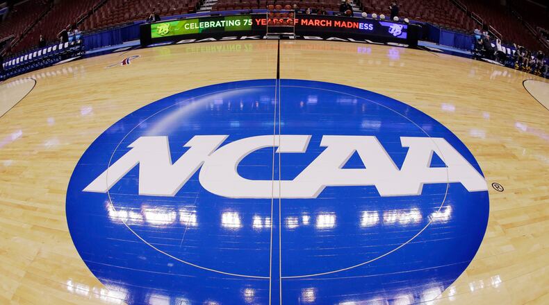 FILE - This photo taken with a fisheye lens shows the NCAA logo displayed at mid-court in Philadelphia, March 21, 2013. (AP Photo/Matt Slocum, File)