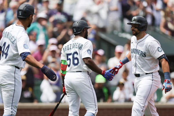 Seattle Mariners designated hitter Cal Raleigh, right, celebrates with Randy Arozarena, center, and Julio Rodriguez, left, after hitting a two-run home run during the first inning of a baseball game against the Pittsburgh Pirates, Friday, July 4, 2025, in Seattle. (AP Photo/Ryan Sun)