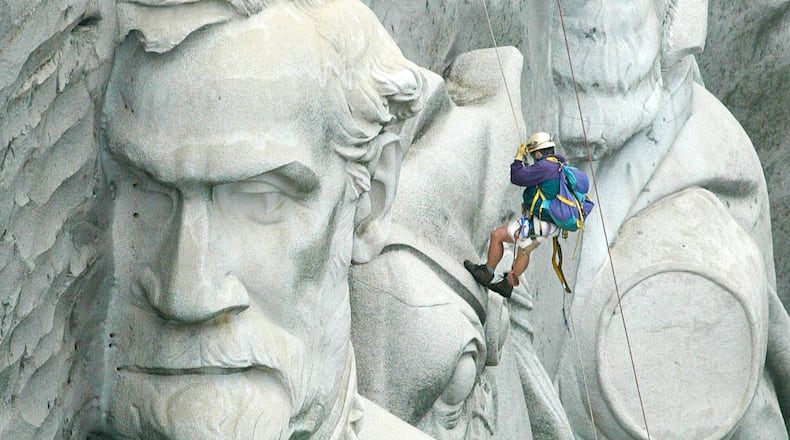 A sandblaster cleaning the carving of three Confederate leaders on Stone Mountain. John Spink, jspink@ajc.com