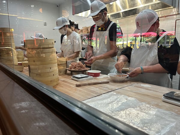 A production line of workers weigh out balls of dough, roll them and fold up to 18 pleats per soup dumpling.