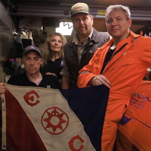 This undated photo provided by the Discovery Channel Tuesday, July 21, 2026, shows, from left, Air/Sea Heritage Foundation (ASHF) President Russ Matthews, ASHF Director Idee Matthews-Montijo, Expedition Unknown's Josh Gates and Deep Sea Visoin President of Operations Craig Wallace inside an AUV hangar with an Explorers Club flag. (Discovery Channel via AP)