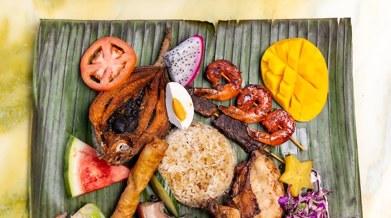 A spread from Boodle Fight at Pullman yards includes milkfish, shrimp and beef skewers, lechon pork belly, chicken inasal and lumpia. (Courtesy of Boodle Fight)