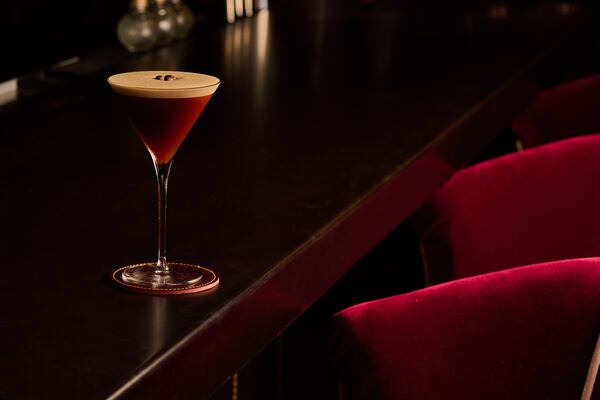 An espresso martini sits on a dimly lit bar